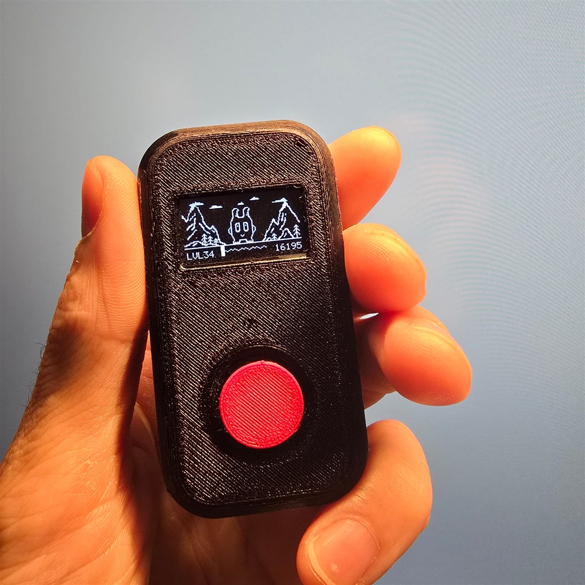 First working CLIX prototype held in hand, showing the monochrome OLED and button